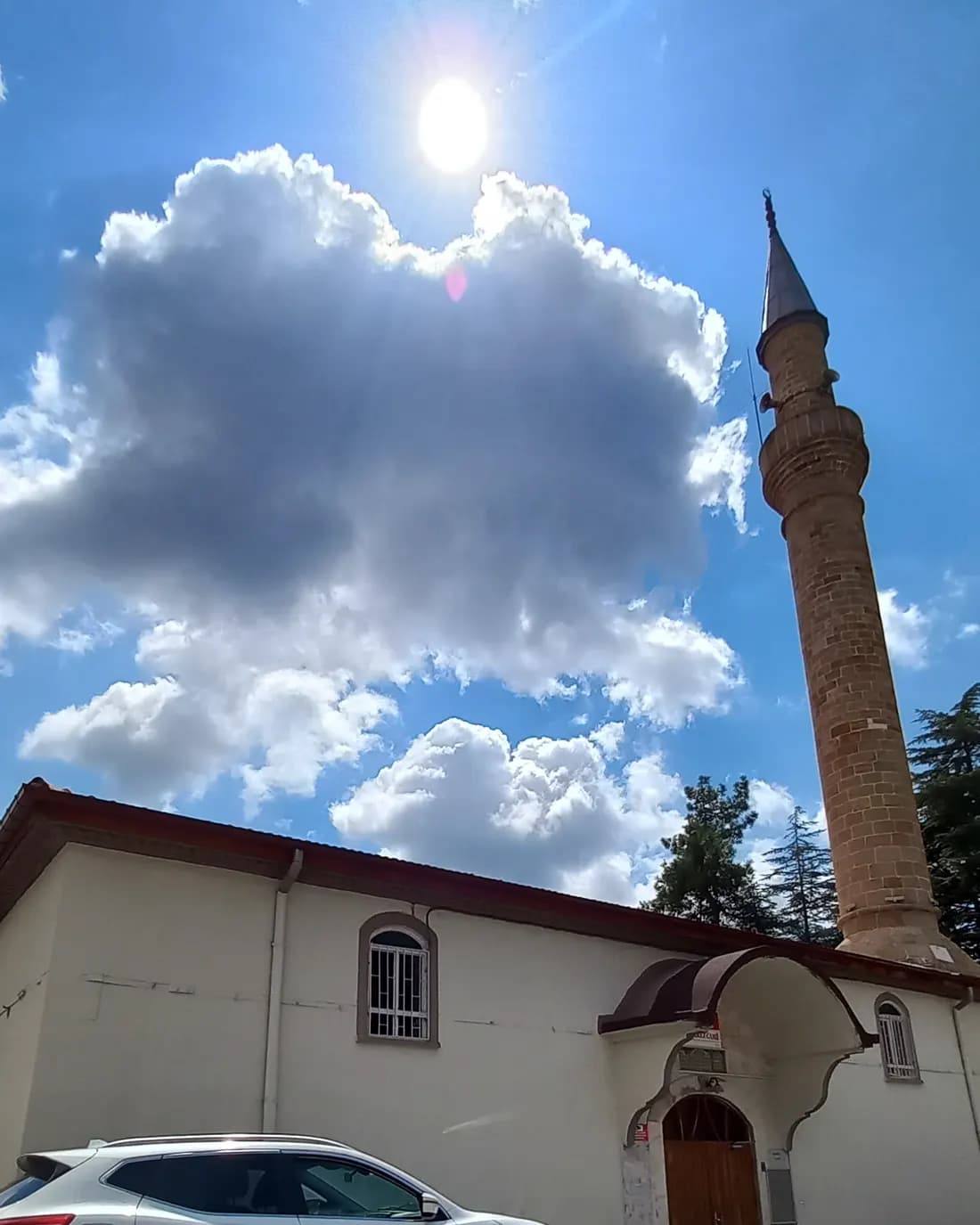 Akseki Merkez Camii'nin beyaz duvarları ve taş minaresi, mavi gökyüzü
