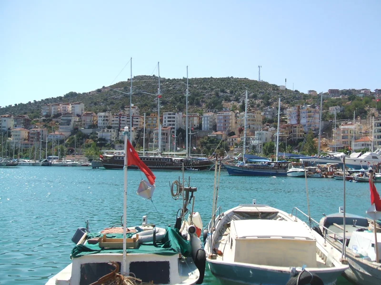 Finike limanında demirli yelkenliler ve tekneler, arkada ilçe merkezi