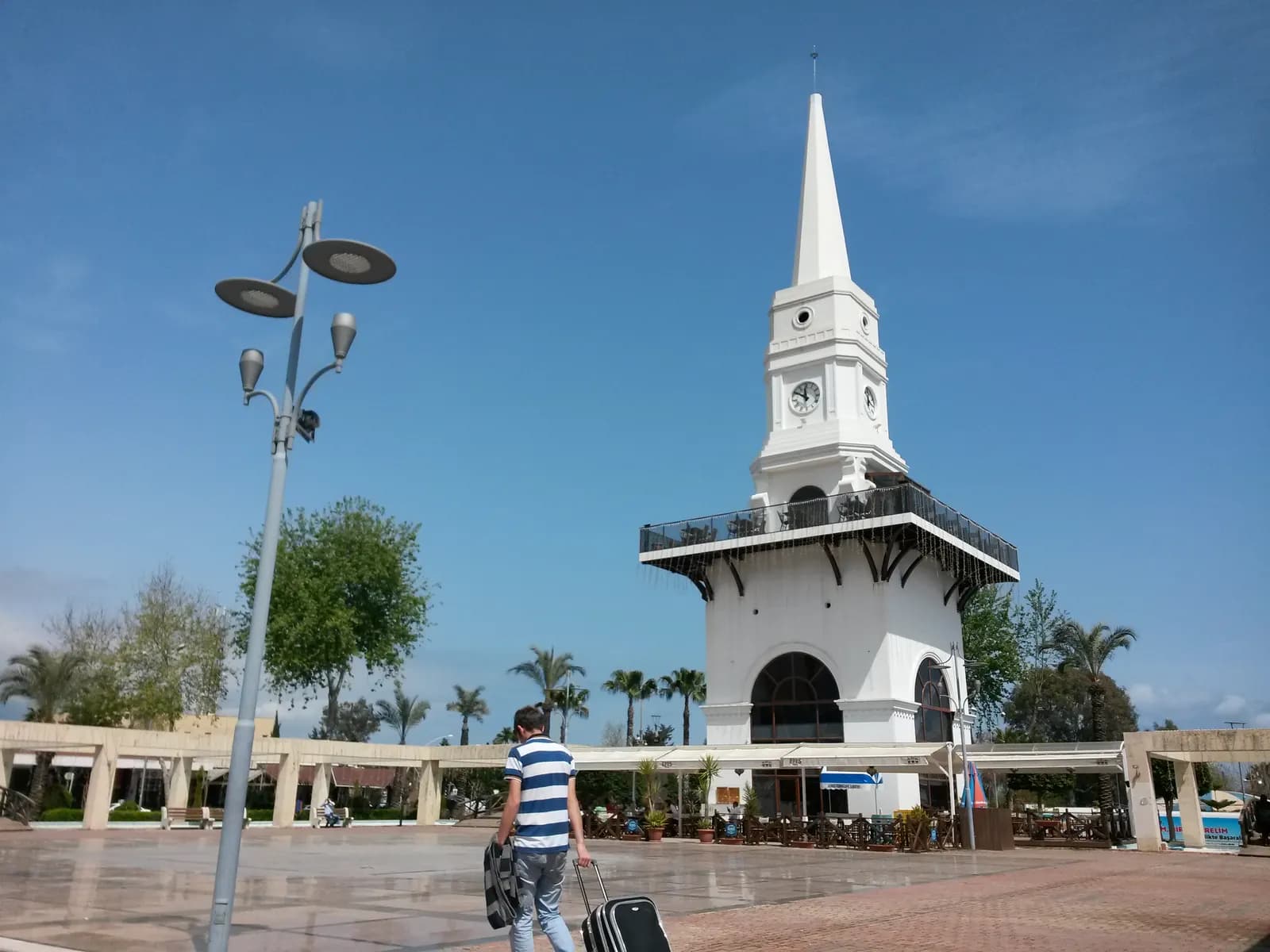 Kemer merkezde palmiyelerle çevrili beyaz saat kulesi ve meydan