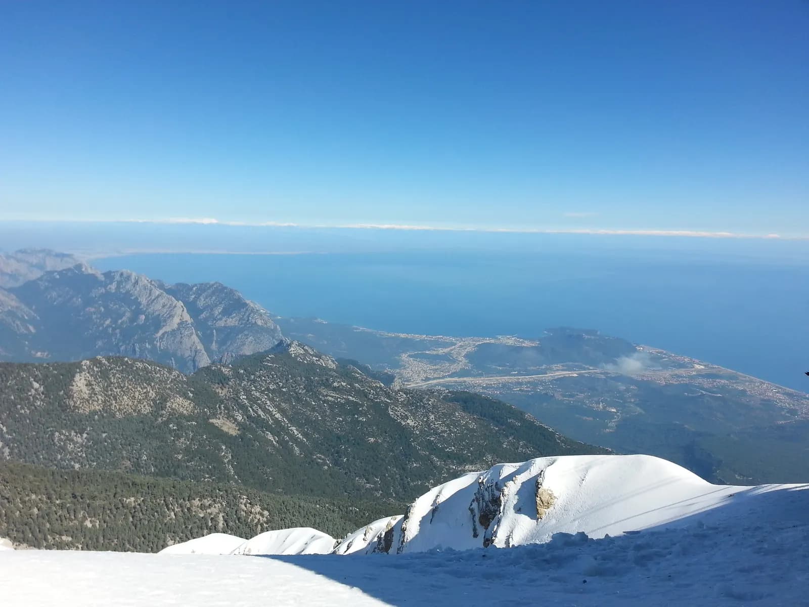 Tahtalı Dağı'nın zirvesinden görülen karlı yamaçlar, Kemer kıyısı ve Akdeniz